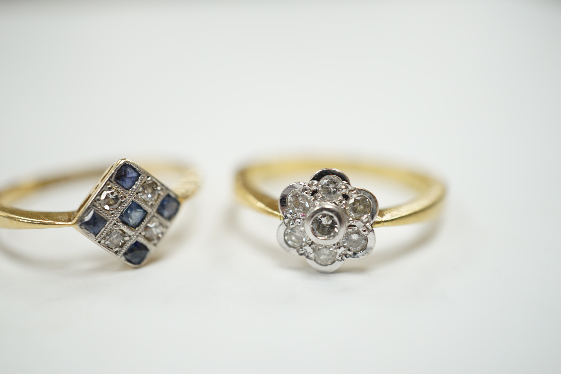 A 1920's 18ct, sapphire and diamond millegrain set cluster ring, size O/P, and a later 18ct gold and seven stone diamond set flower head cluster ring, gross weight 6.3 grams.